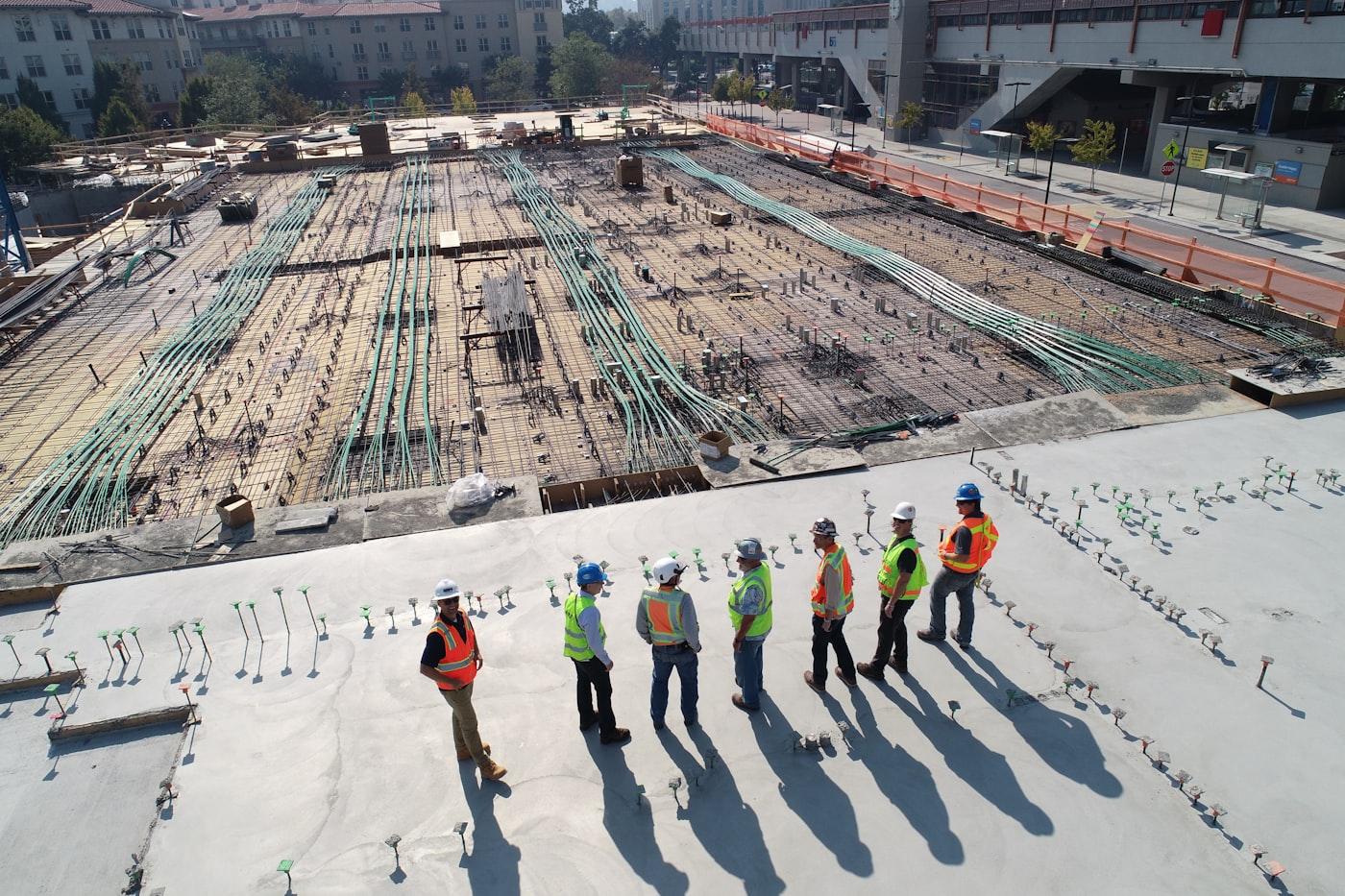 Construction team in safety gear surveying a large building site